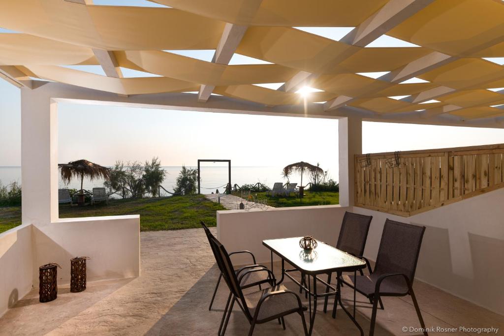 a dining room with a table and chairs on a patio at Seashore Stream Suites in Alykes