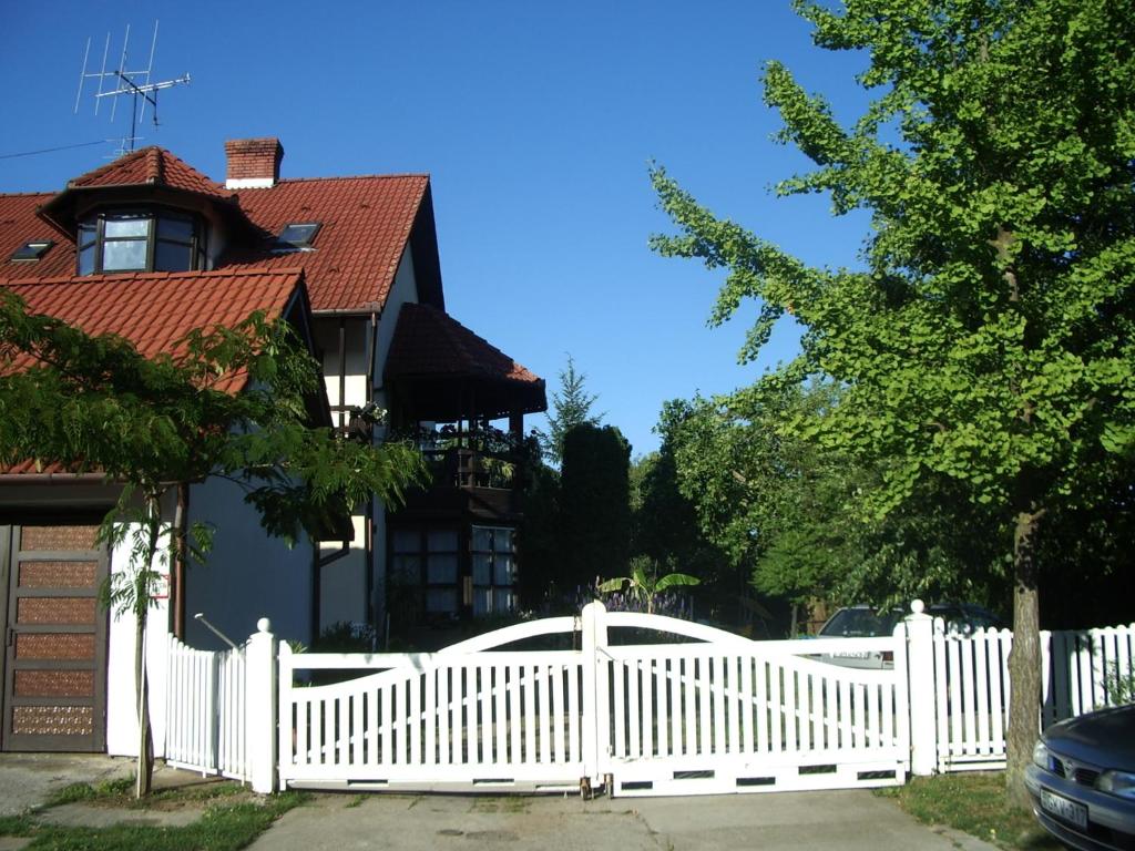 una cerca blanca frente a una casa en Apartmanház Gabriella, en Harkány
