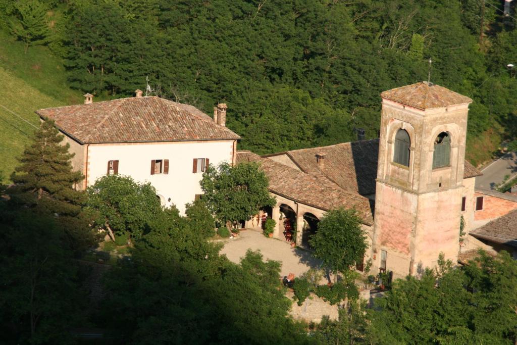 um grande edifício branco com uma torre de relógio numa colina em Antica Locanda La Canonica em Zocca