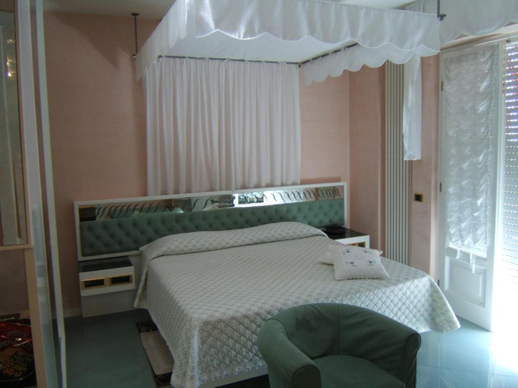 um quarto com uma cama e uma cadeira verde em Hotel Matilde em Marina di Massa