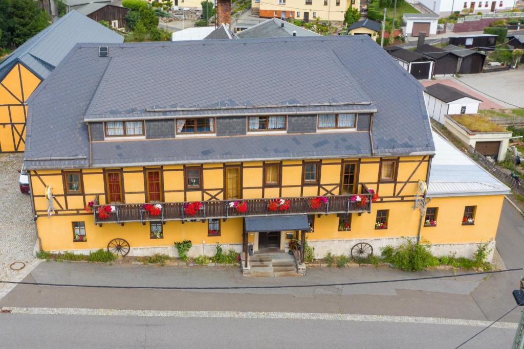 a yellow house with red flowers on a balcony at Landhotel Quelle in Heidersdorf