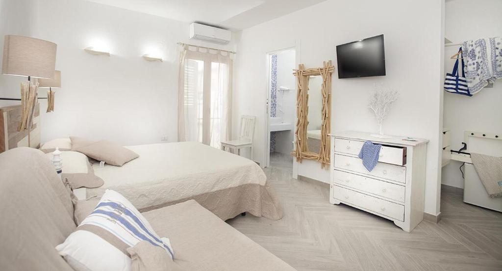 Habitación blanca con cama y espejo en B&B Jolie en Santa Teresa Gallura