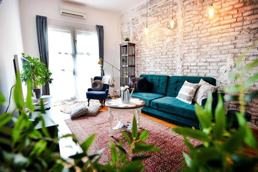 a living room with a blue couch and a brick wall at Villa Inda Rooms in Eger