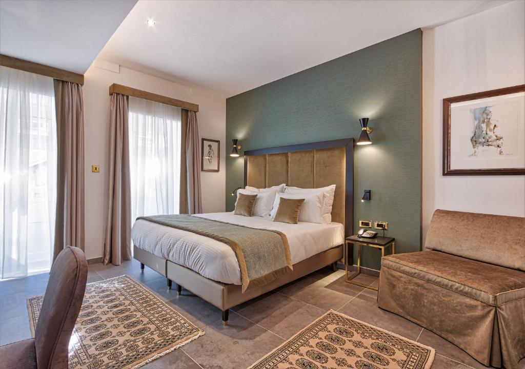 a bedroom with a bed and a chair and a couch at Palazzo Rosaria Boutique Hotel in Valletta