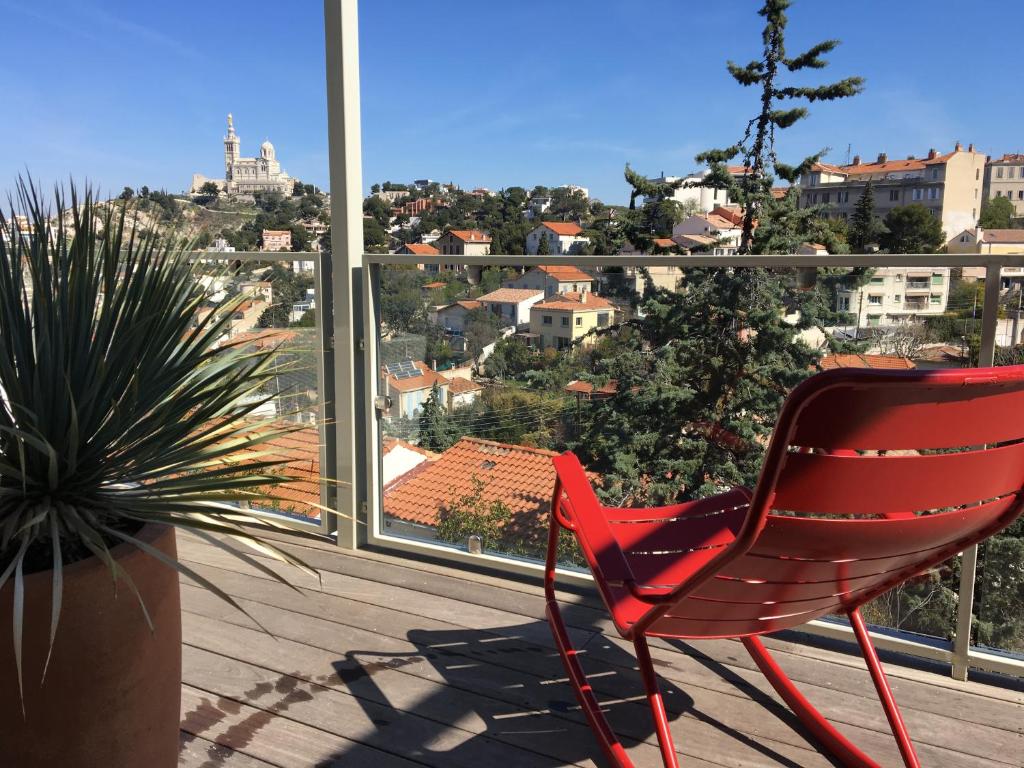 une chaise rouge assise sur un balcon avec vue dans l'établissement Villa Yvonne - Superbe vue Deco chic Confort et Climatisation, à Marseille