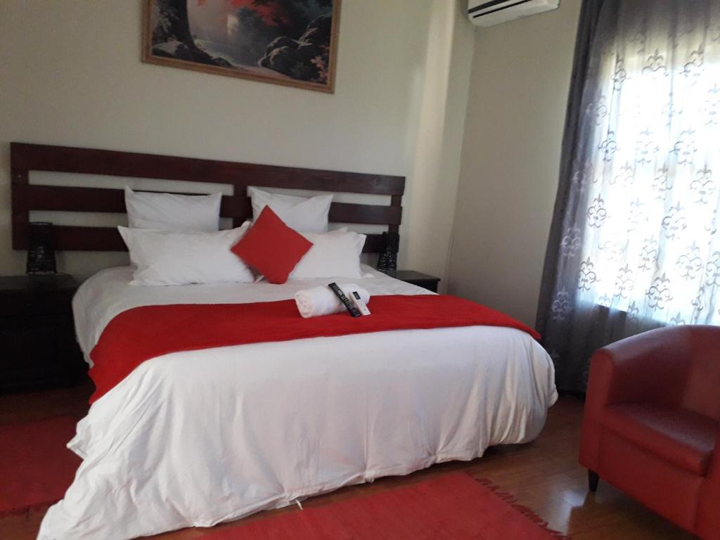 1 dormitorio con 1 cama con manta roja en Ikaze Guest House, en Boksburg