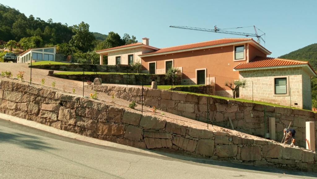 un cane seduto sopra un muro di pietra di Casa dos Codessos a Ribeira de Pena