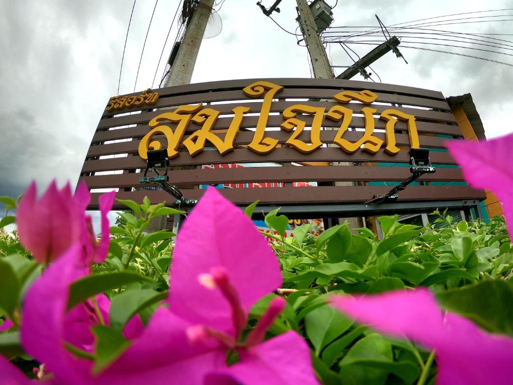 Um sinal para um restaurante com flores cor-de-rosa à frente. em Somjainuk Resort 2 em Pluak Daeng