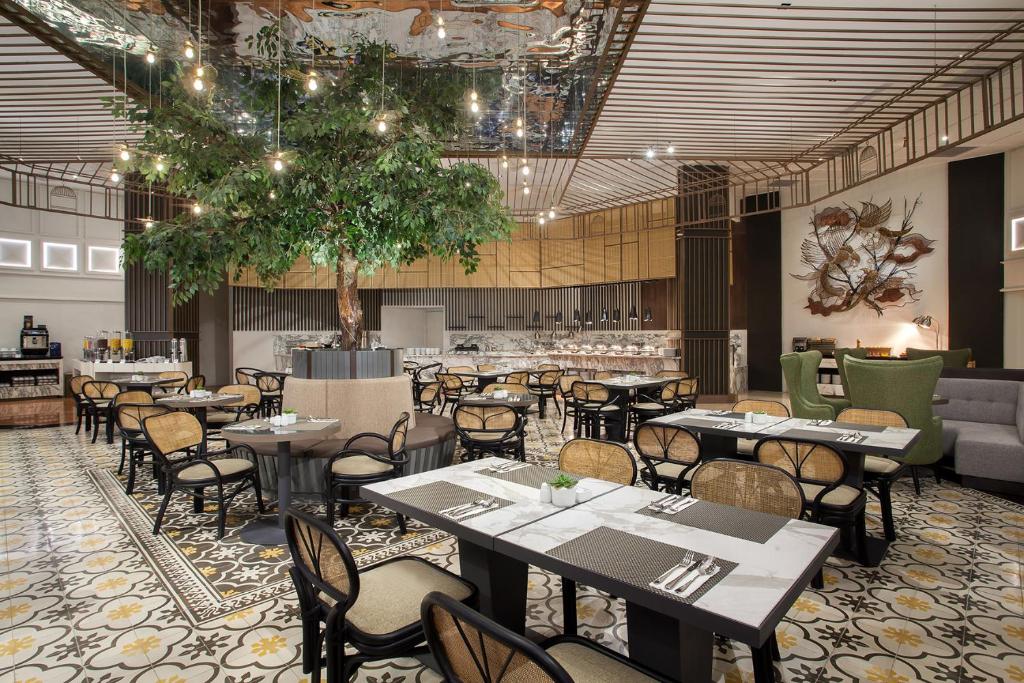 a restaurant with tables and chairs in a room at Mercure Jakarta Batavia in Jakarta