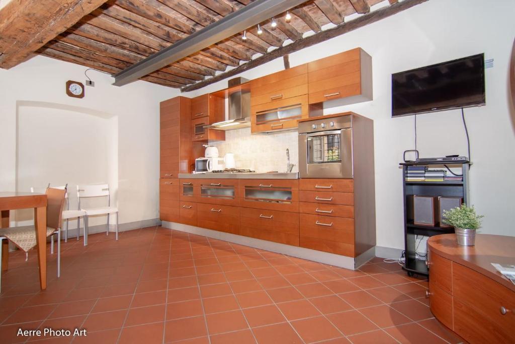 een keuken met houten kasten en een flatscreen-tv bij Casa Gemma in Lucca