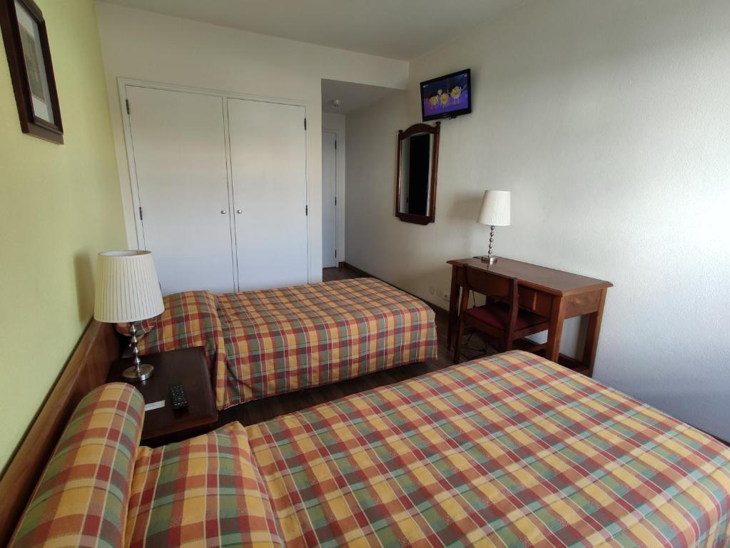 a hotel room with two beds and a desk at Mafra Guest House in Mafra