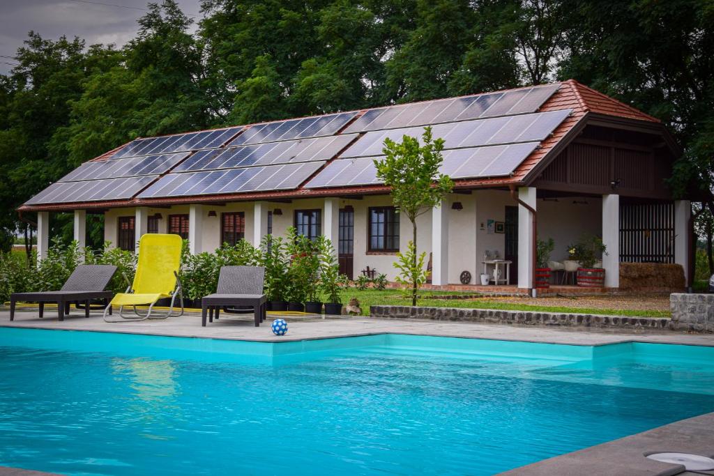 a house with solar panels on top of a swimming pool at Leveleki Vendégház - Egeres Tanya in Levelek