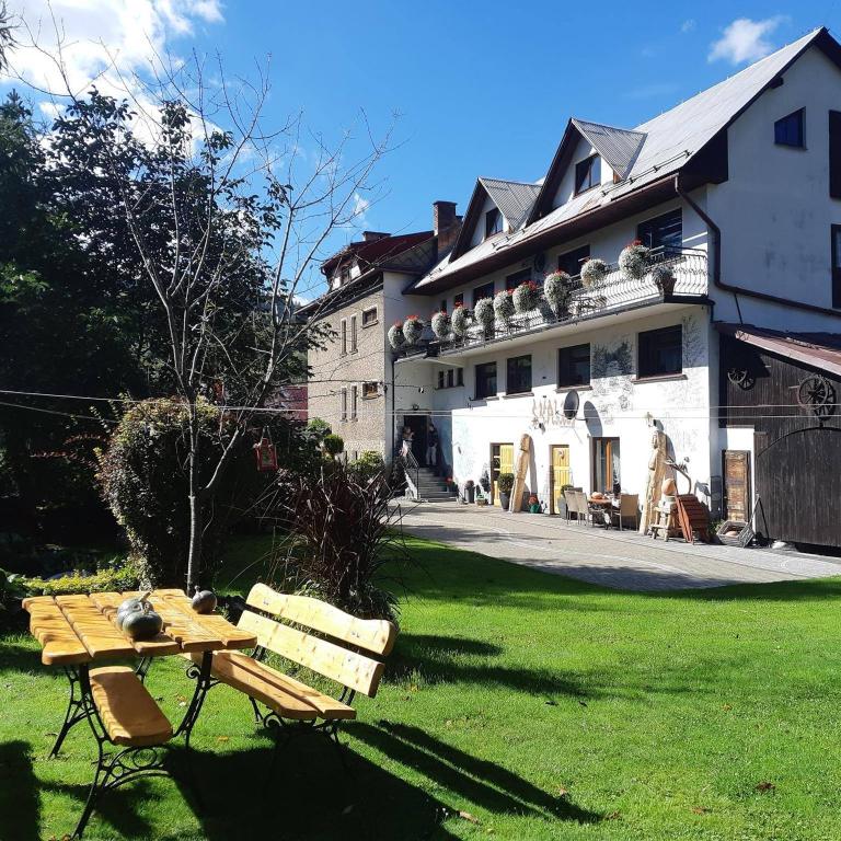a building with a table and benches in a yard at Pokoje Gościnne Skalny Agroturystyka in Żabnica