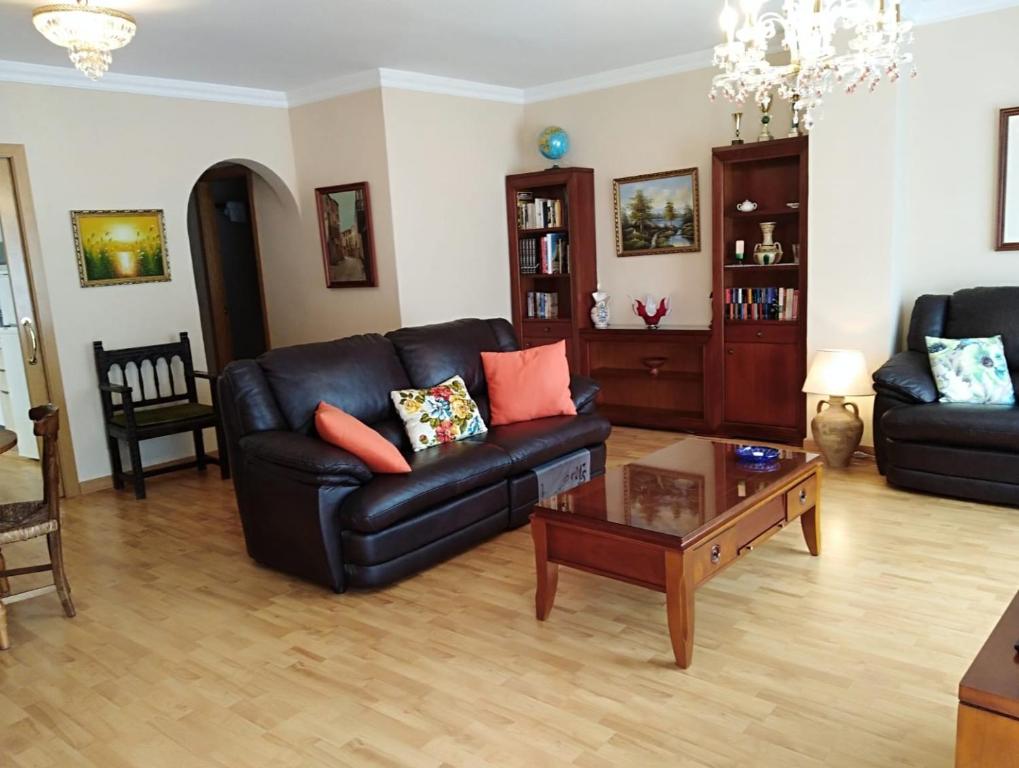 Sala de estar con sofá de cuero negro y mesa de centro en CAL SOLÉ, en Ulldemolins
