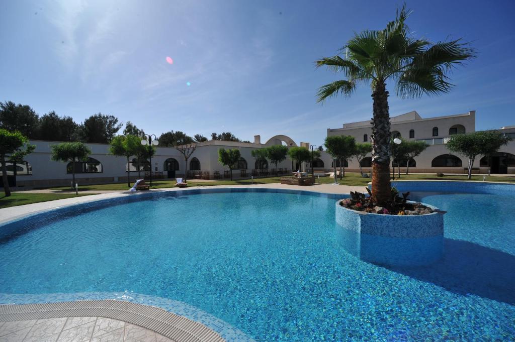 una gran piscina con una palmera frente a un edificio en Laurito Resort & Spa, en Oria