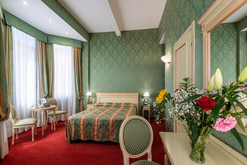 pokój hotelowy z łóżkiem, stołem i krzesłami w obiekcie Hotel Villa Delle Palme w Lido di Venezia