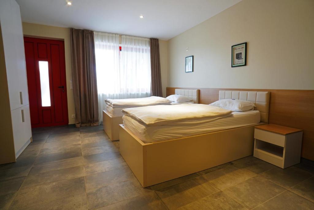 twee bedden in een kamer met een rode deur bij Nava Motel & Storage in Wiener Neustadt
