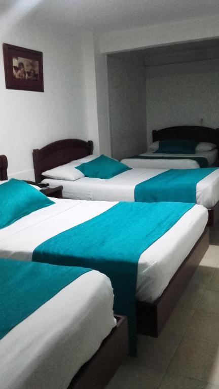 a hotel room with three beds with blue and white sheets at Hotel Center in Ibagué