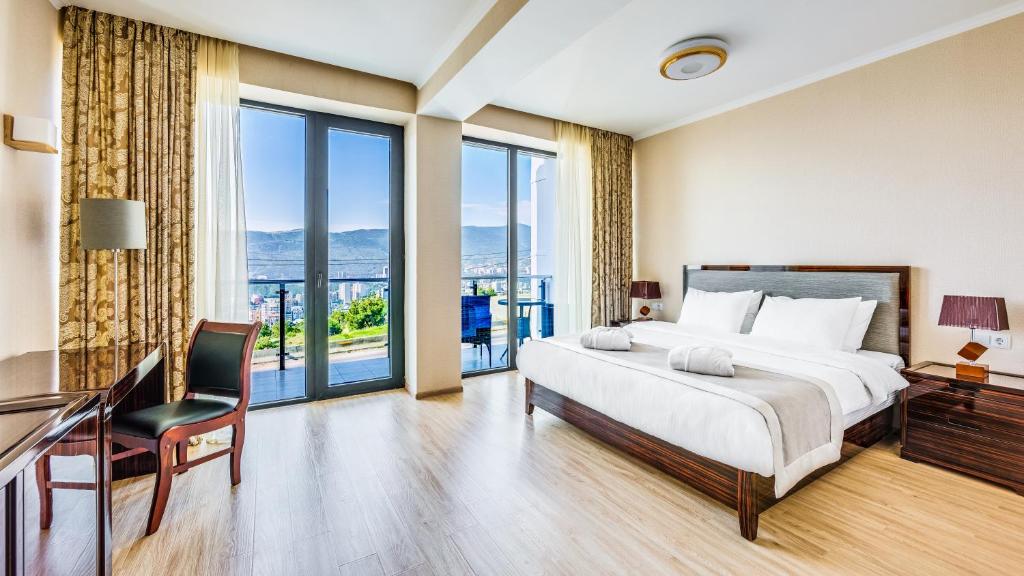 a bedroom with a bed and a desk and windows at Lisi Hills Hotel in Tbilisi City