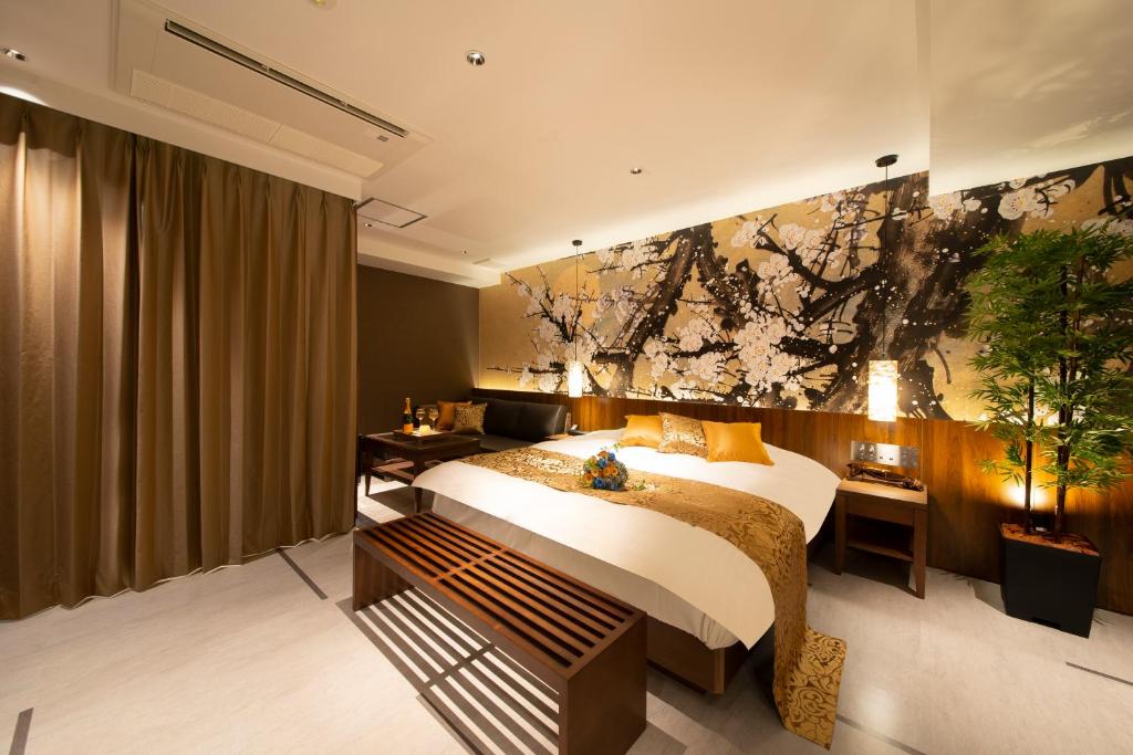 1 dormitorio con 1 cama y una pintura en la pared en ホテル Tiger & Dragon 男塾ホテルグループ, en Gifu