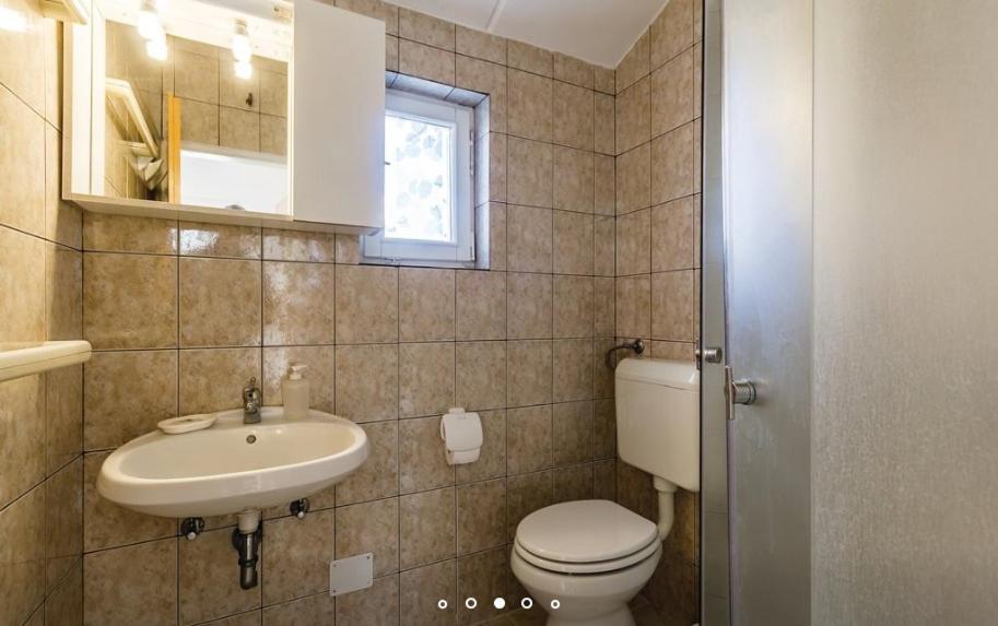 łazienka z umywalką, toaletą i oknem w obiekcie House Hermes w mieście Pavicini