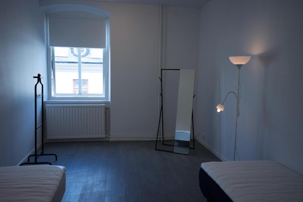 a room with two beds and a mirror and a window at Jönköping Vandrarhem in Jönköping