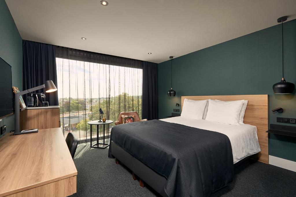 a bedroom with a bed and a large window at Van der Valk Hotel Antwerpen in Antwerp