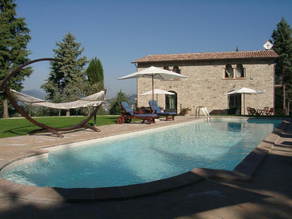 a swimming pool with a hammock in front of a house at Podere Caldaruccio La Pineta in Bosco