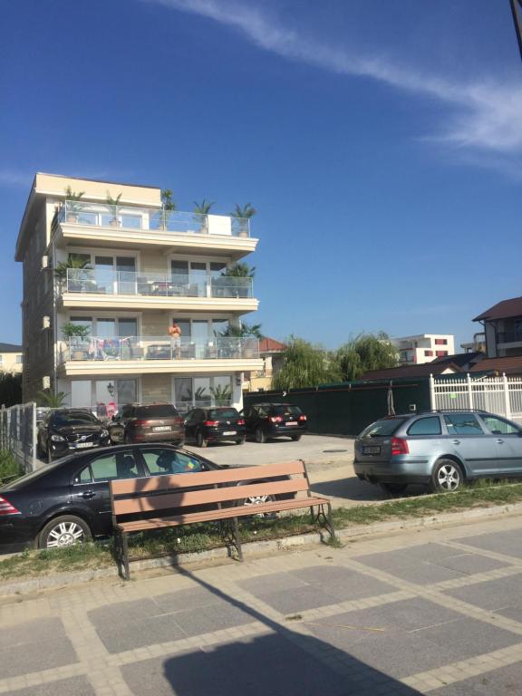 een bankje op een parkeerplaats voor een gebouw bij Briza pe promenada in Mamaia Nord – Năvodari