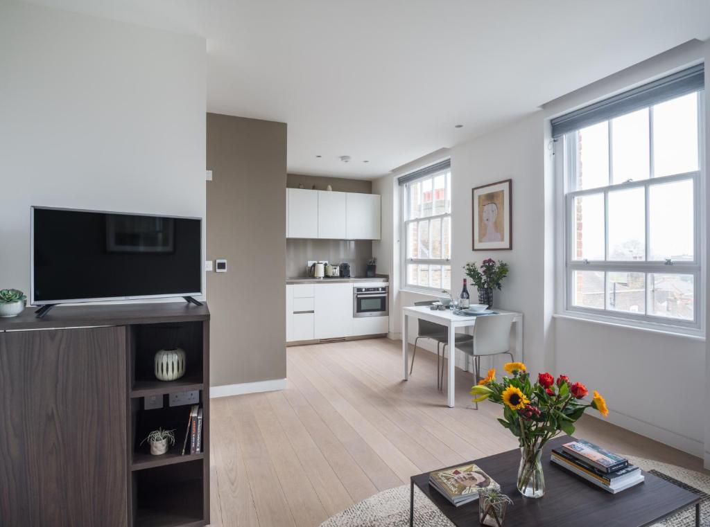 a living room with a television and a table at Mirabilis Apartments, Wells Court in London