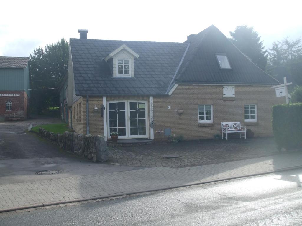 a brown house with a black roof on a street at Appartement Dorfstrasse in Glücksburg