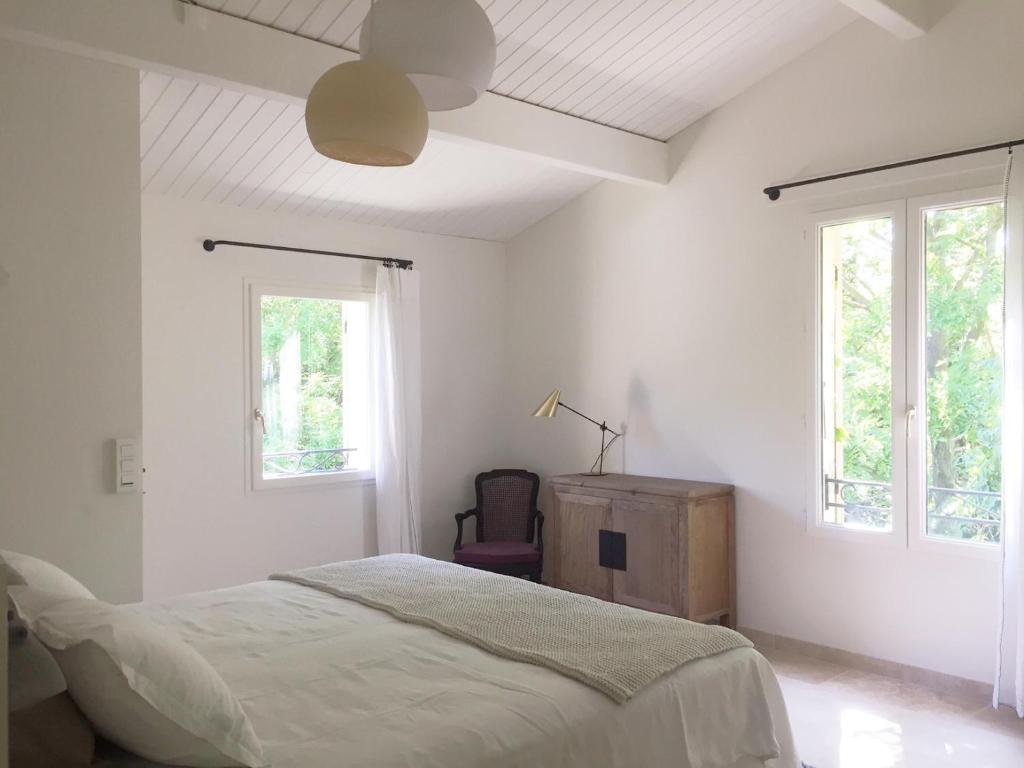 a white bedroom with a bed and two windows at Serendip in Avignon
