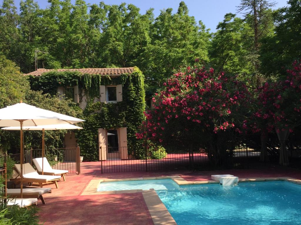 a swimming pool in front of a house with pink flowers at Serendip in Avignon