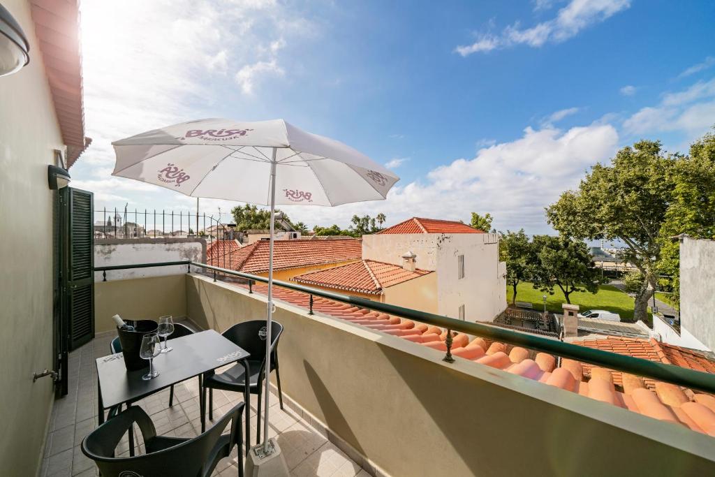 a patio with a table and an umbrella on a balcony at OurMadeira - Taberna Apartments, old town in Funchal