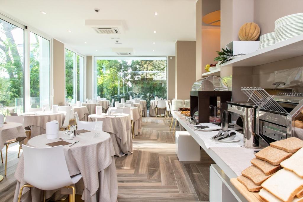 a restaurant with white tables and white chairs at Hotel Greif in Lido di Jesolo