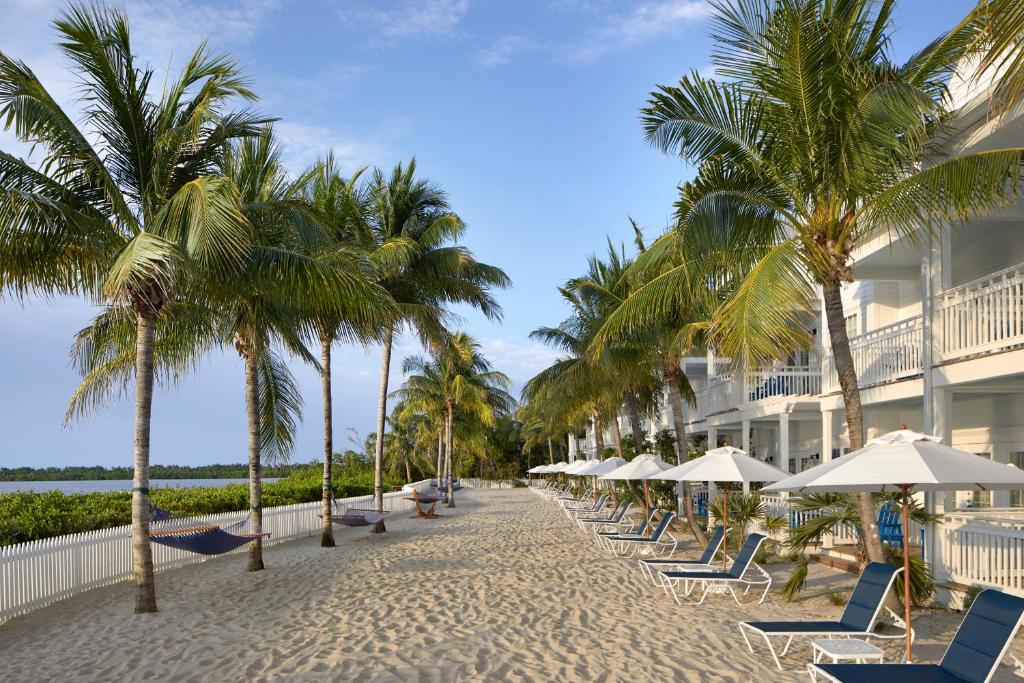 a beach with chairs and palm trees and a building at Parrot Key Hotel & Villas in Key West
