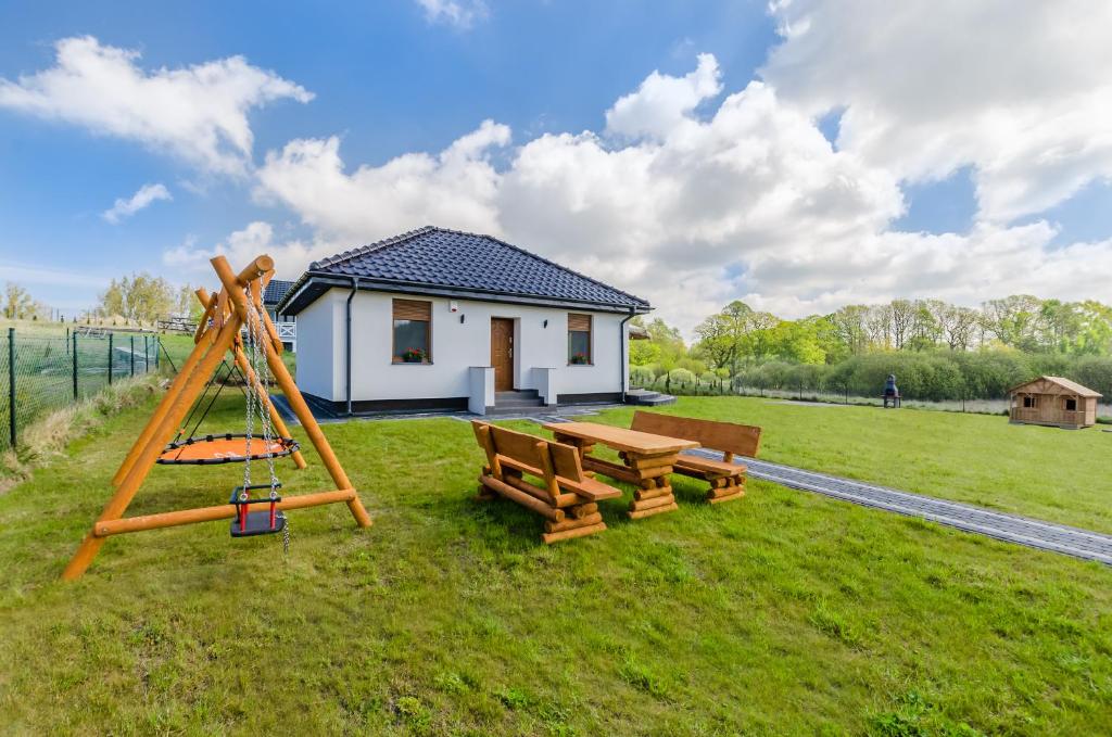 a picnic table and a swing in front of a house at Nadmorskie Zacisze in Dębina