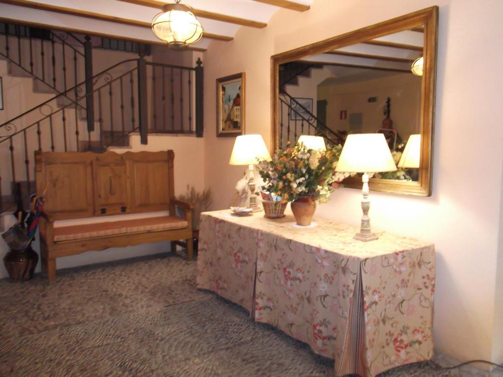 a room with a table with flowers and a mirror at Apartamentos Clavería in Biniés