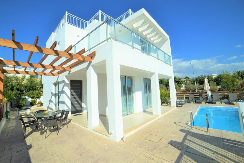 a white house with a swimming pool and a patio at Coral Bay Villa 10 in Coral Bay