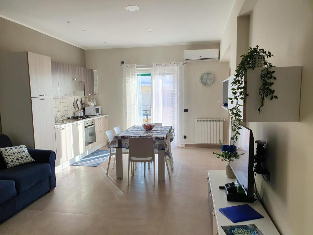 a kitchen and living room with a table and a blue couch at The Sweet Home of Milazzo in Milazzo