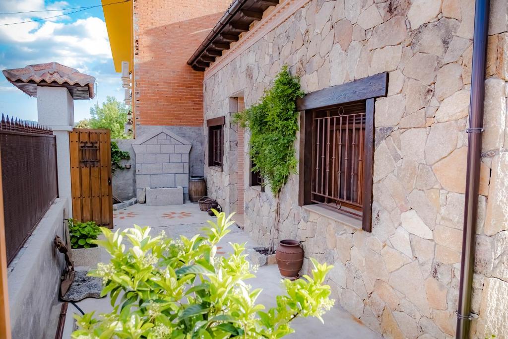 un edificio de piedra con una ventana y algunas plantas en Casa Los 5 Caños, en Sotillo de la Adrada