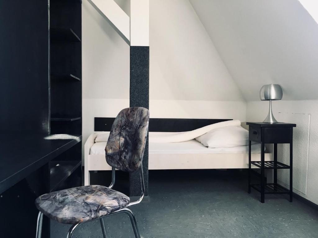 a bedroom with a bed and a chair at Pension Akropolis in Rellingen