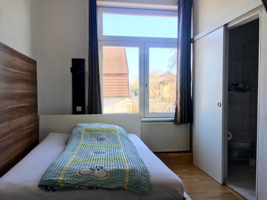 ein Schlafzimmer mit einem Bett und einem großen Fenster in der Unterkunft Pension Akropolis in Rellingen