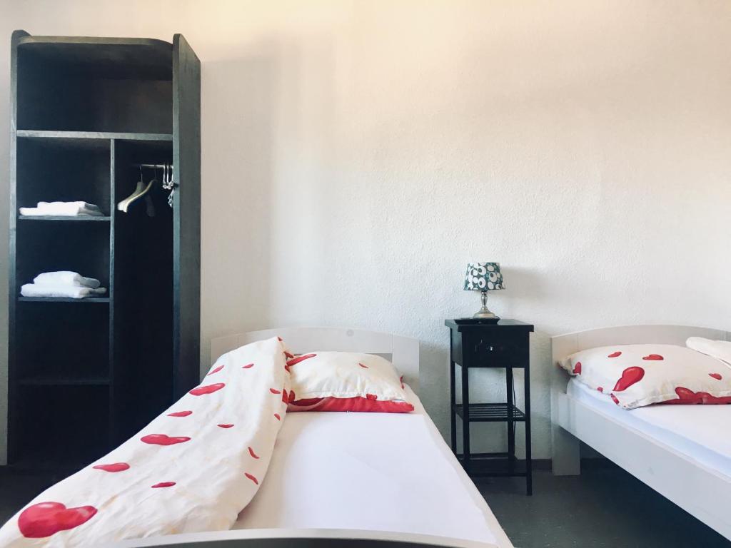ein Schlafzimmer mit 2 Betten und einem schwarzen Regal in der Unterkunft Pension Akropolis in Rellingen