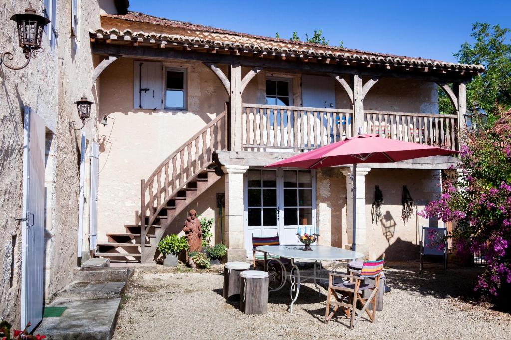 Montagnac-la-Crempse的住宿－Logis Saint Martin，房屋前设有带桌子和遮阳伞的天井。