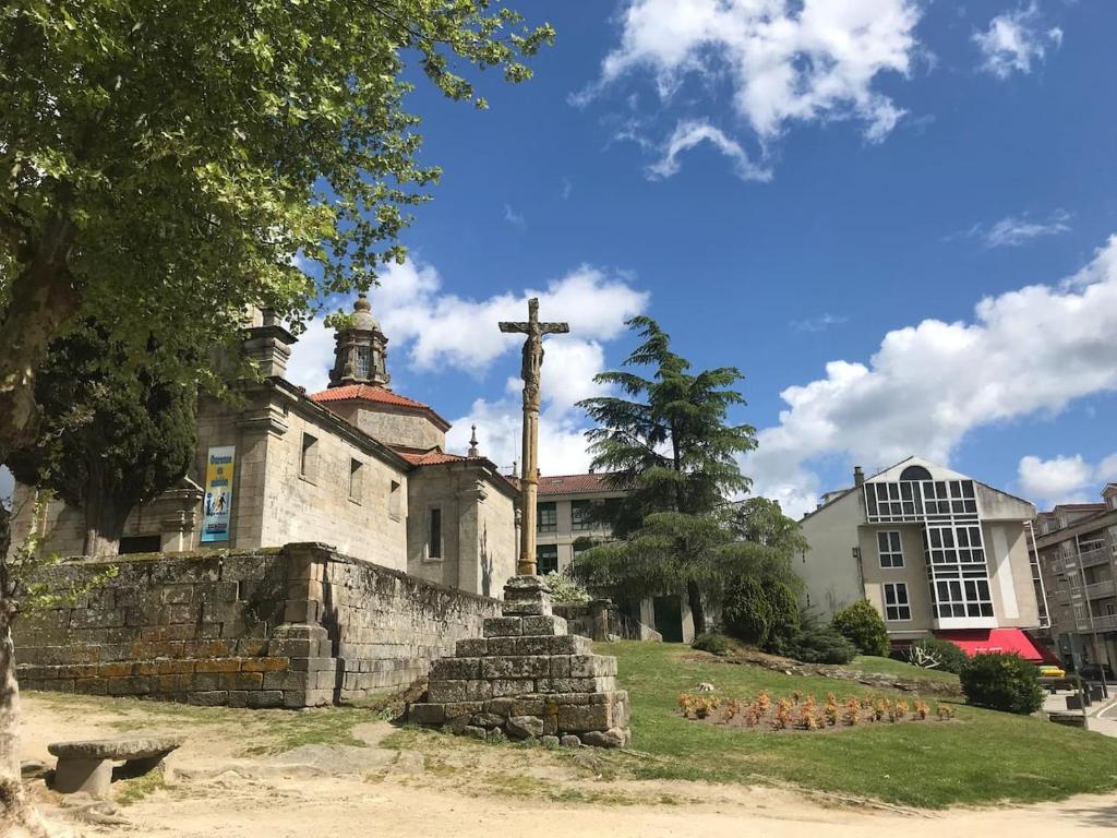 Una vieja iglesia con una cruz encima. en Atico Emilia Pardo Bazán en Allariz