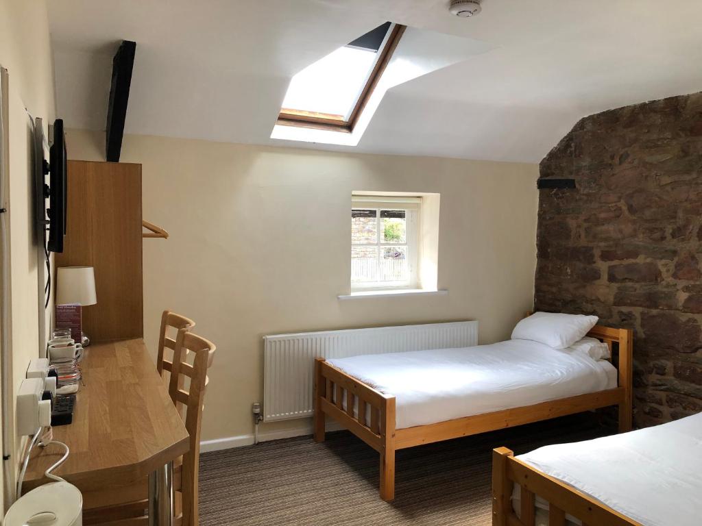 a bedroom with a bed, a desk and a window at Butchers Arms in Coleford