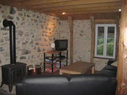 uma sala de estar com um sofá e uma parede de pedra em Gite Clara em Bassignac-le-Haut