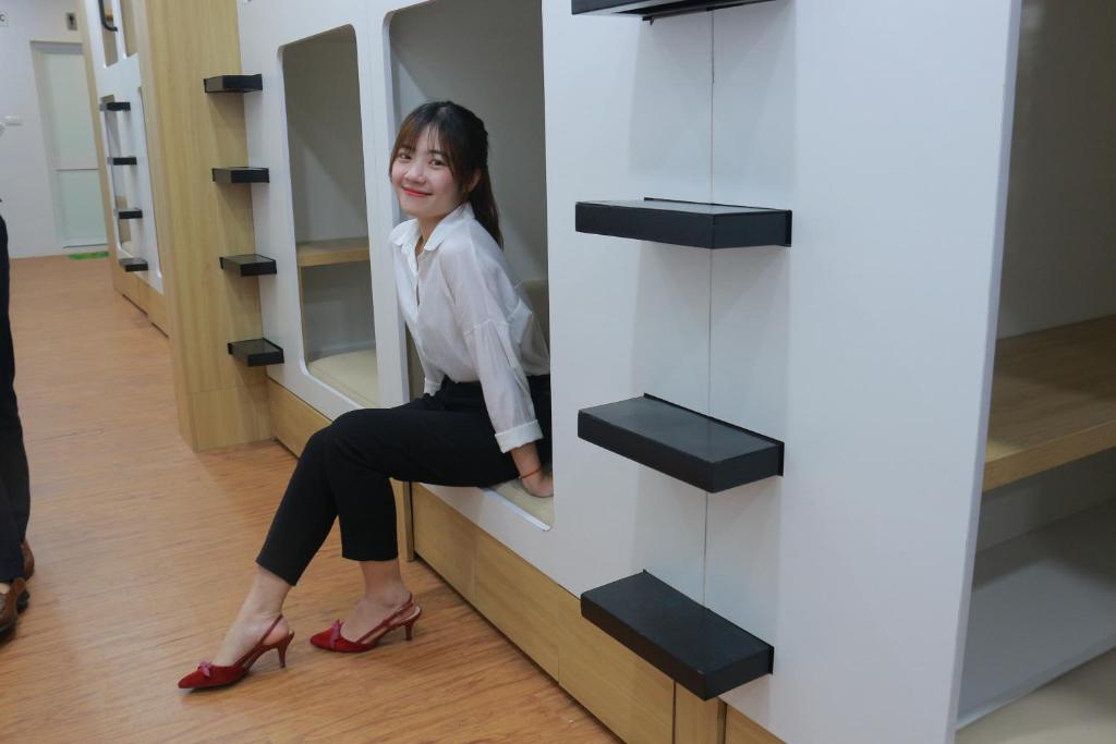 a woman sitting on a shelf in a store at Techgarden Workstay Dorm - Coworking Space in Hanoi