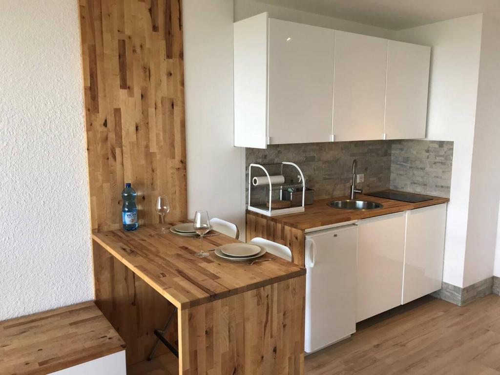 a kitchen with white cabinets and a wooden counter top at PERCHOIR 1 : Studio haut de gamme et lumineux in Turckheim